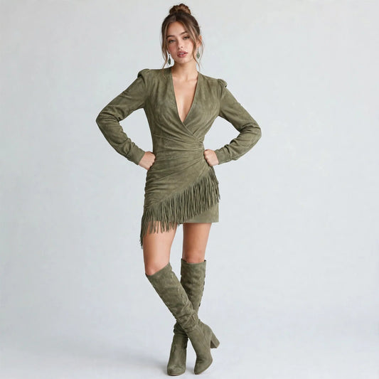 Woman with hands on hips in an olive green long-sleeve fringe mini dress with V-neckline and matching boots, gray studio.