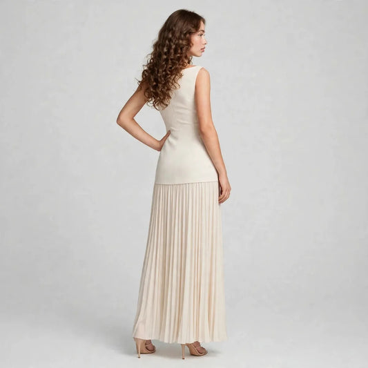 Back view of a cream sleeveless pleated maxi dress with fitted bodice, model standing against a gray studio backdrop.
