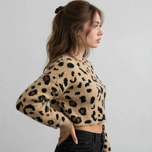 Side profile of a tan leopard fuzzy knit cropped sweater with black jeans, model's hand in pocket, gray studio background.