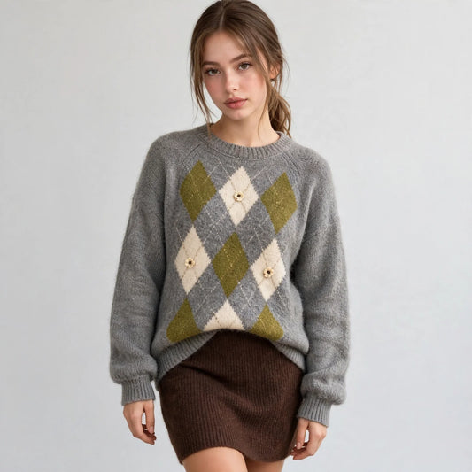 Front view of a grey argyle knit sweater with raglan sleeves and diamond pattern, brown skirt, white studio backdrop.