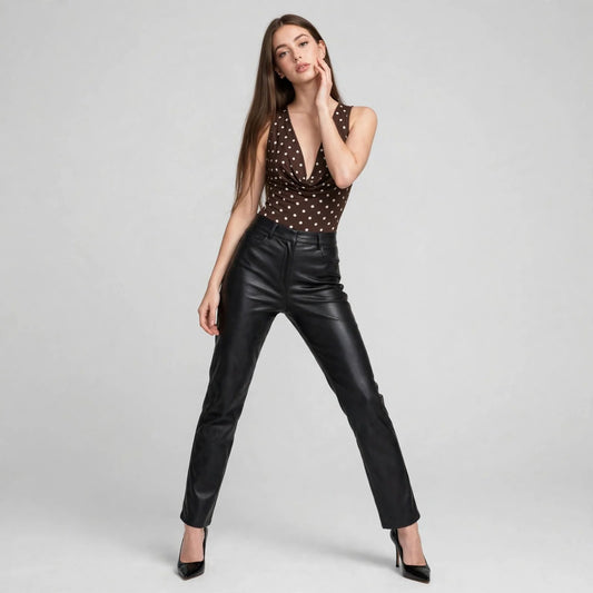 Full front view of a brown polka dot cowl neck bodysuit styled with black leather pants and heels, white studio backdrop.