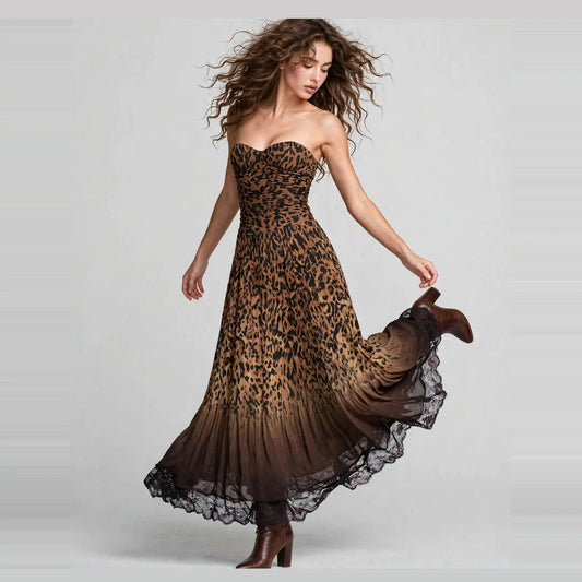 Woman twirling and lifting her skirt in a strapless leopard-print maxi dress with black ombré hem and boots, gray studio.