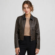 Woman in a brown leopard-print cropped faux leather jacket with black collar and utility pockets, black pants, gray studio.