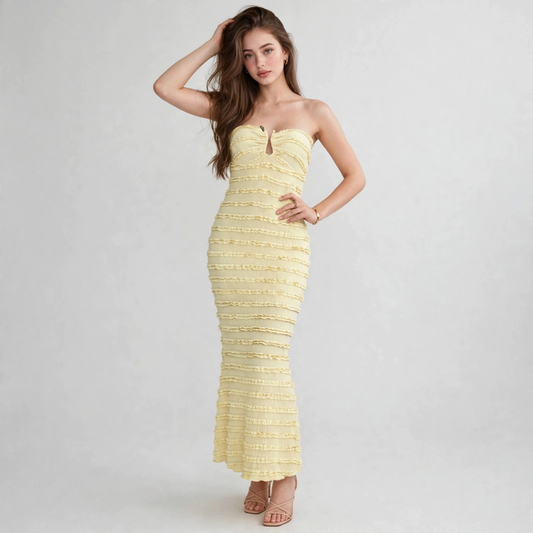 Woman posing in a strapless pale yellow ruched maxi dress with textured finish, sweetheart neckline and fitted silhouette.