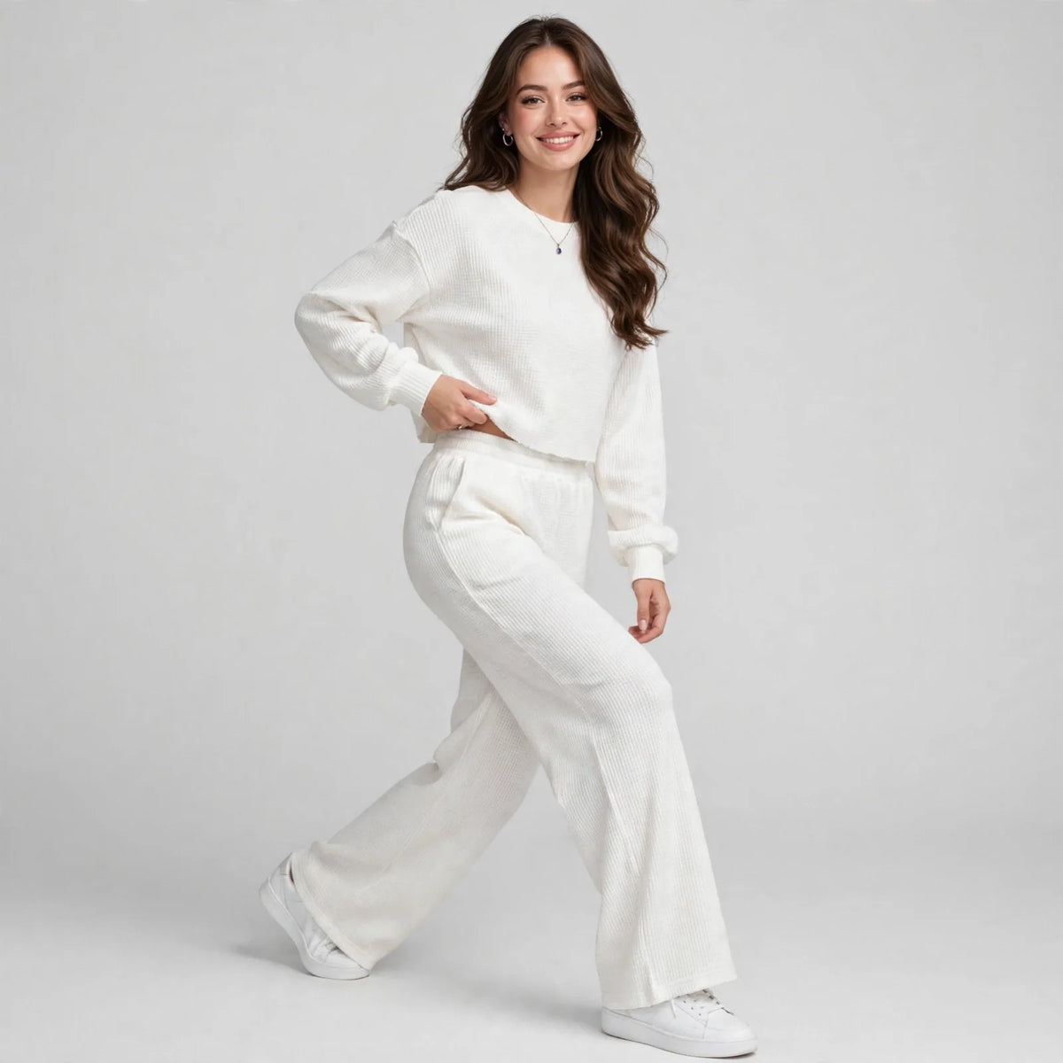 Model walking in white waffle-knit cropped top and wide-leg pants loungewear set, full-body front view, studio shot.