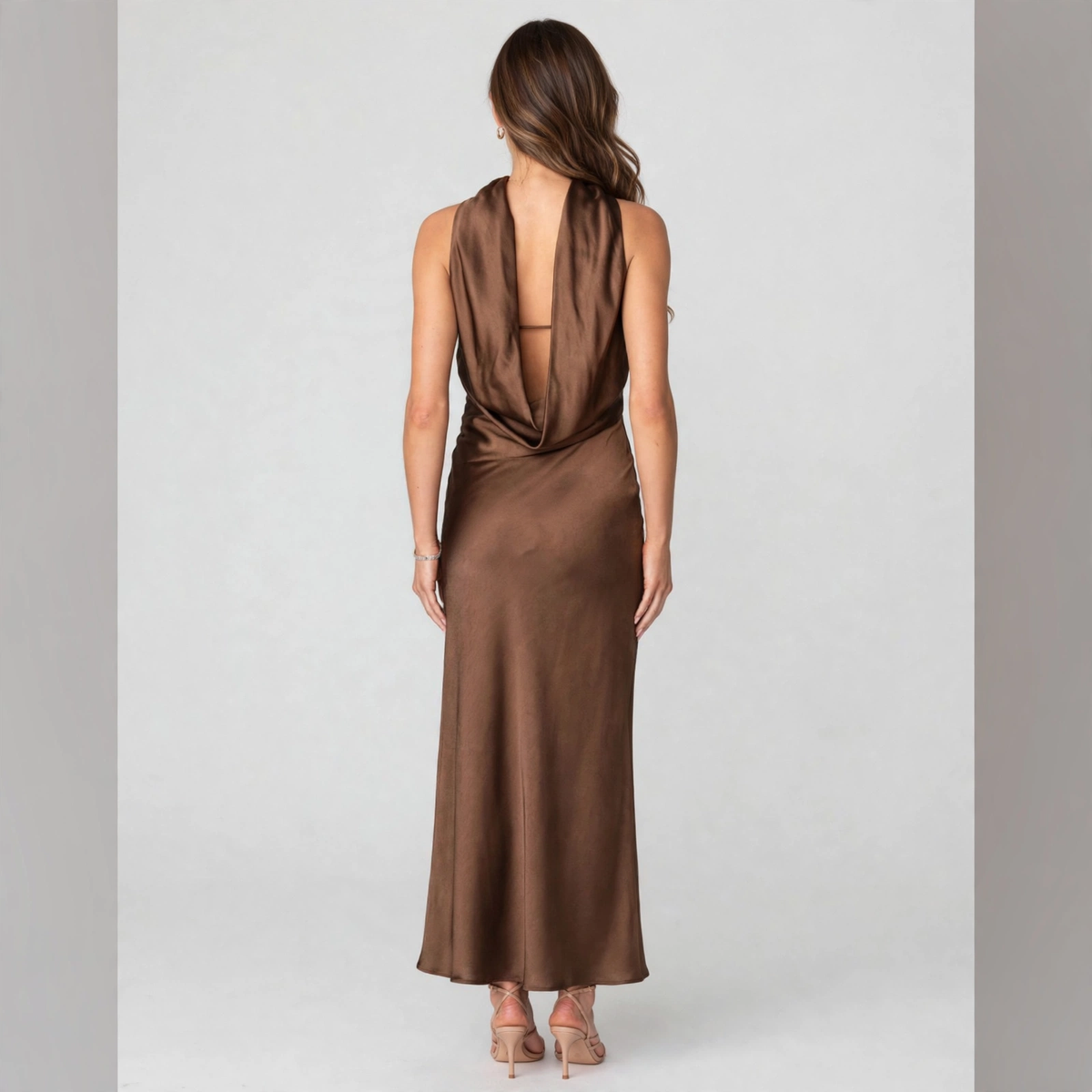 Back view of a brown satin strapless maxi dress with draped open back and choker neckline, white studio backdrop.