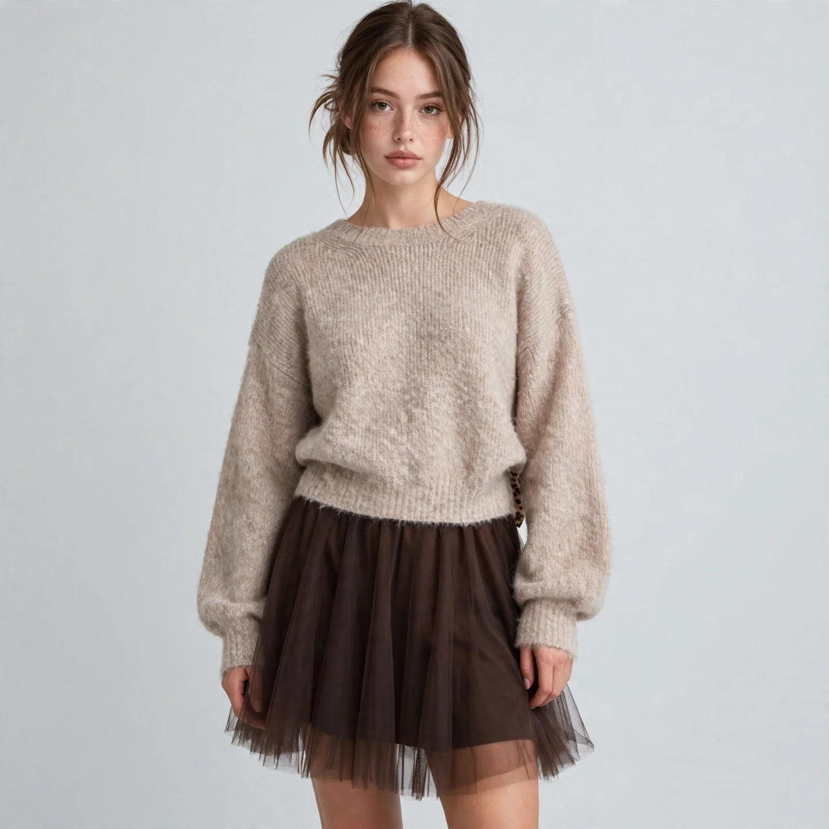 Full front view of model in beige fuzzy dropped-shoulder knit sweater with relaxed fit, light grey studio backdrop.