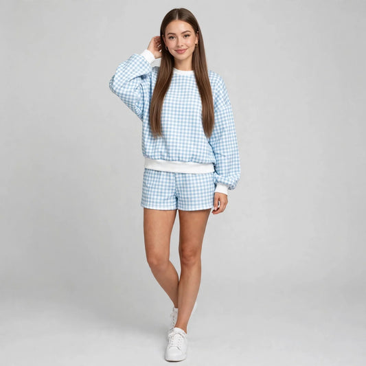 Front view of a light blue and white gingham sweatshirt and shorts set with white ribbed trim, white sneakers, studio.