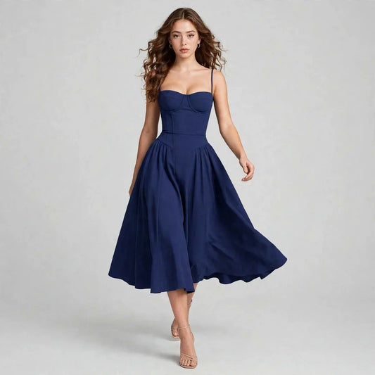 Model walking in a navy sweetheart neck ruched midi dress with spaghetti straps and flared skirt, front view, grey background
