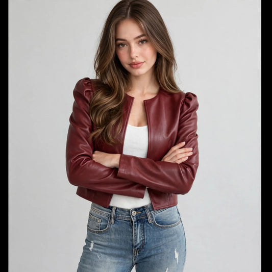 Model with arms crossed in a burgundy open-front faux leather puff-sleeve jacket over a white top and jeans, gray background.