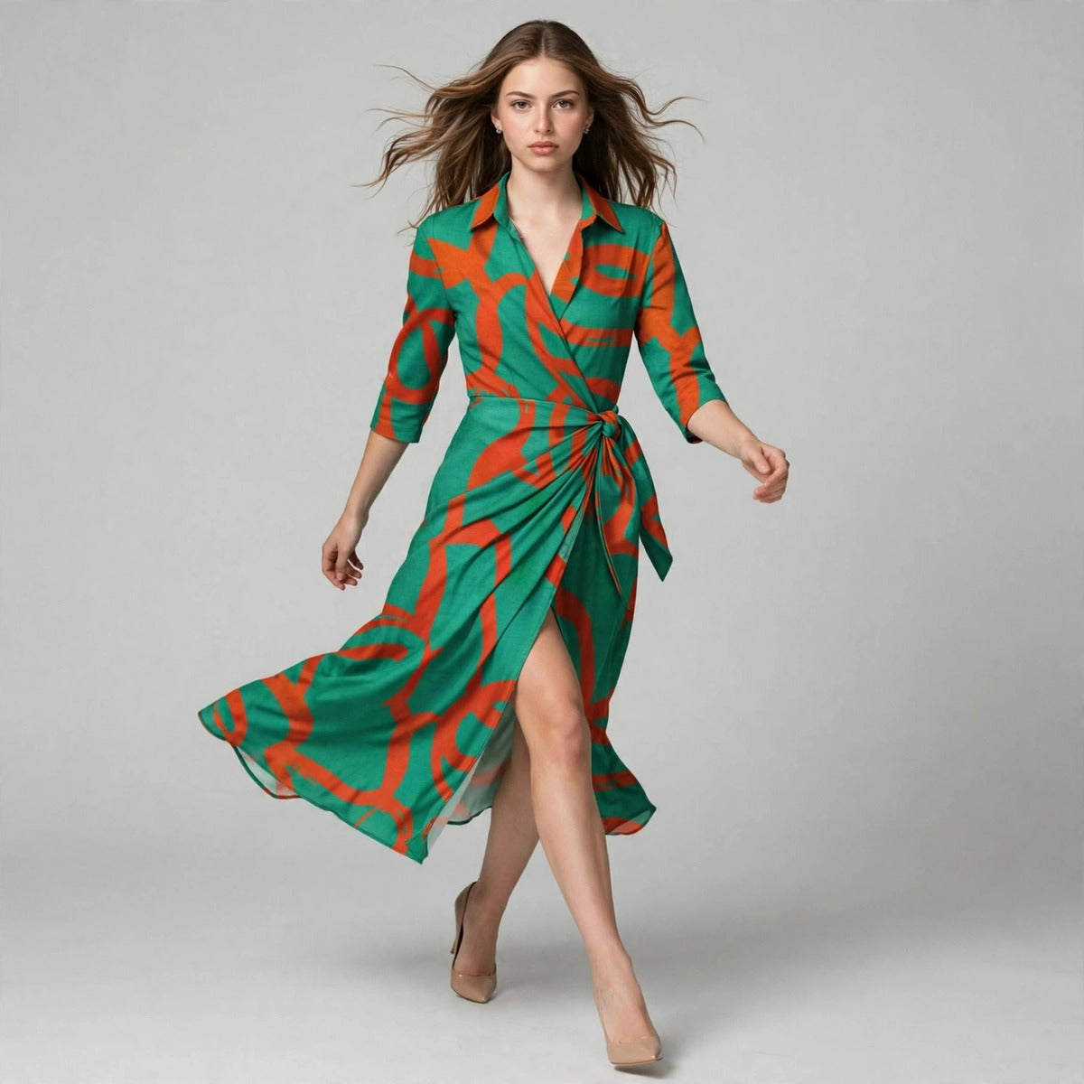 Full-length walking view of a woman in a green shirt dress with orange abstract print and wrap-style tie waist.