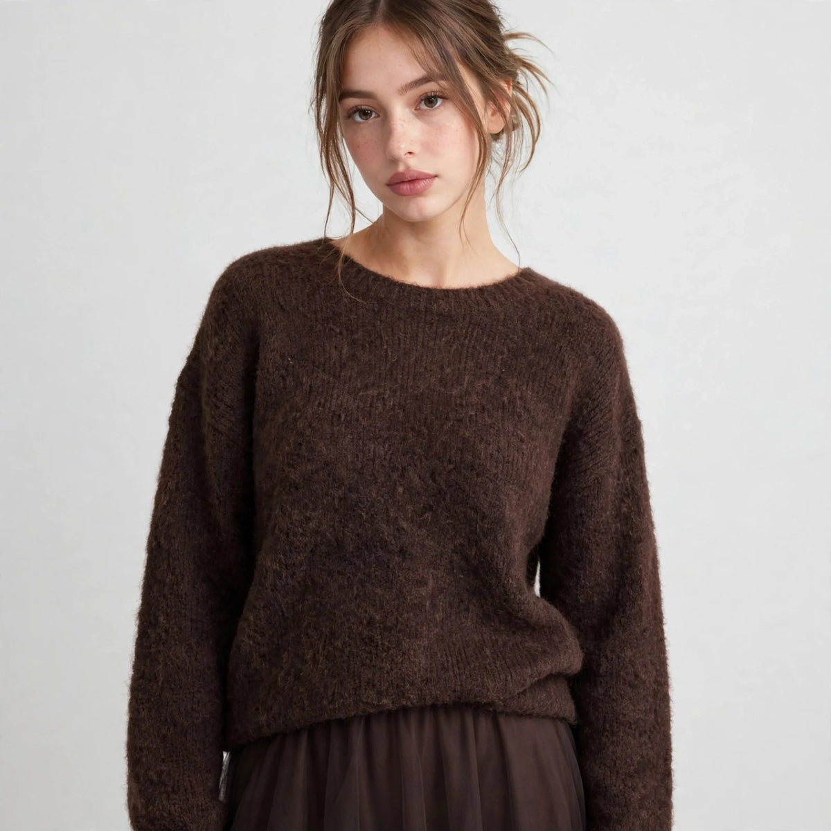 Front view of brown fuzzy dropped-shoulder knit sweater with round neckline on model, light grey studio backdrop.