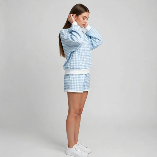 Side view of a light blue gingham two-piece lounge set with long-sleeve sweatshirt and matching shorts, gray studio.