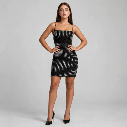 Model in black rhinestone bodycon mini dress with spaghetti straps and square neckline, front view, studio backdrop.
