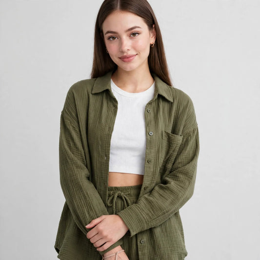 Close-up of a woman wearing an olive green textured button-up shirt over a white ribbed crop top, gray studio background.