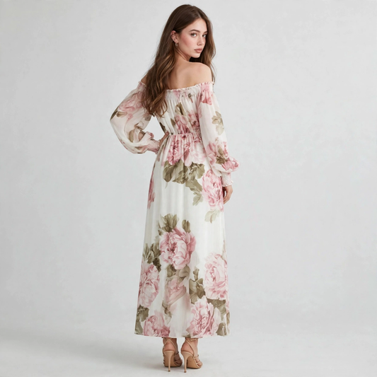 Three-quarter view of woman in white and pink floral off-shoulder maxi dress with balloon sleeves, grey studio backdrop.