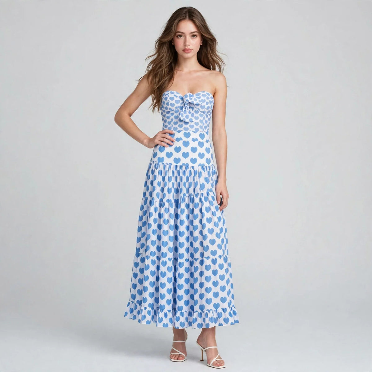 Front view of a blue heart-print strapless one-piece swimsuit with matching tiered maxi skirt on a model, gray studio.