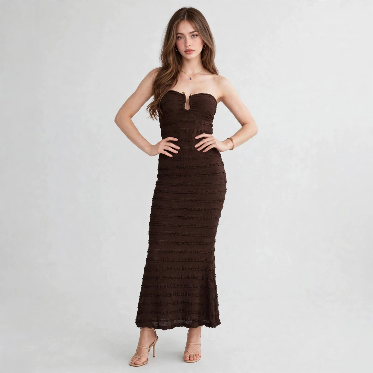 Woman modeling a strapless dark brown textured maxi dress with ruched bodice, sweetheart neckline and keyhole at bust.