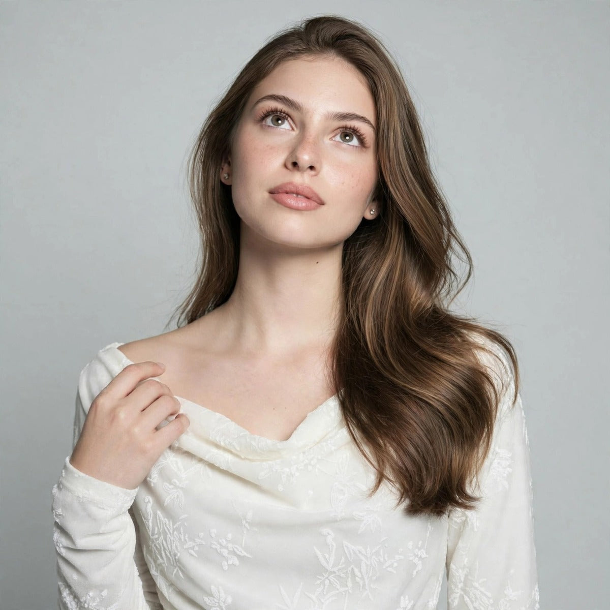 Close-up of a white ruched mini dress showing the draped off-shoulder neckline and textured fabric detail on the model.