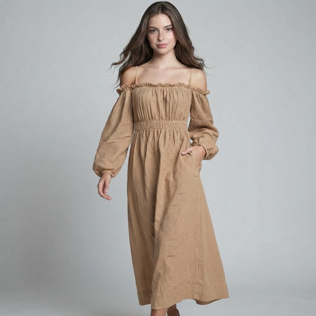 Woman modeling a tan off-shoulder midi dress with balloon sleeves and smocked bodice, hand in pocket, gray background.