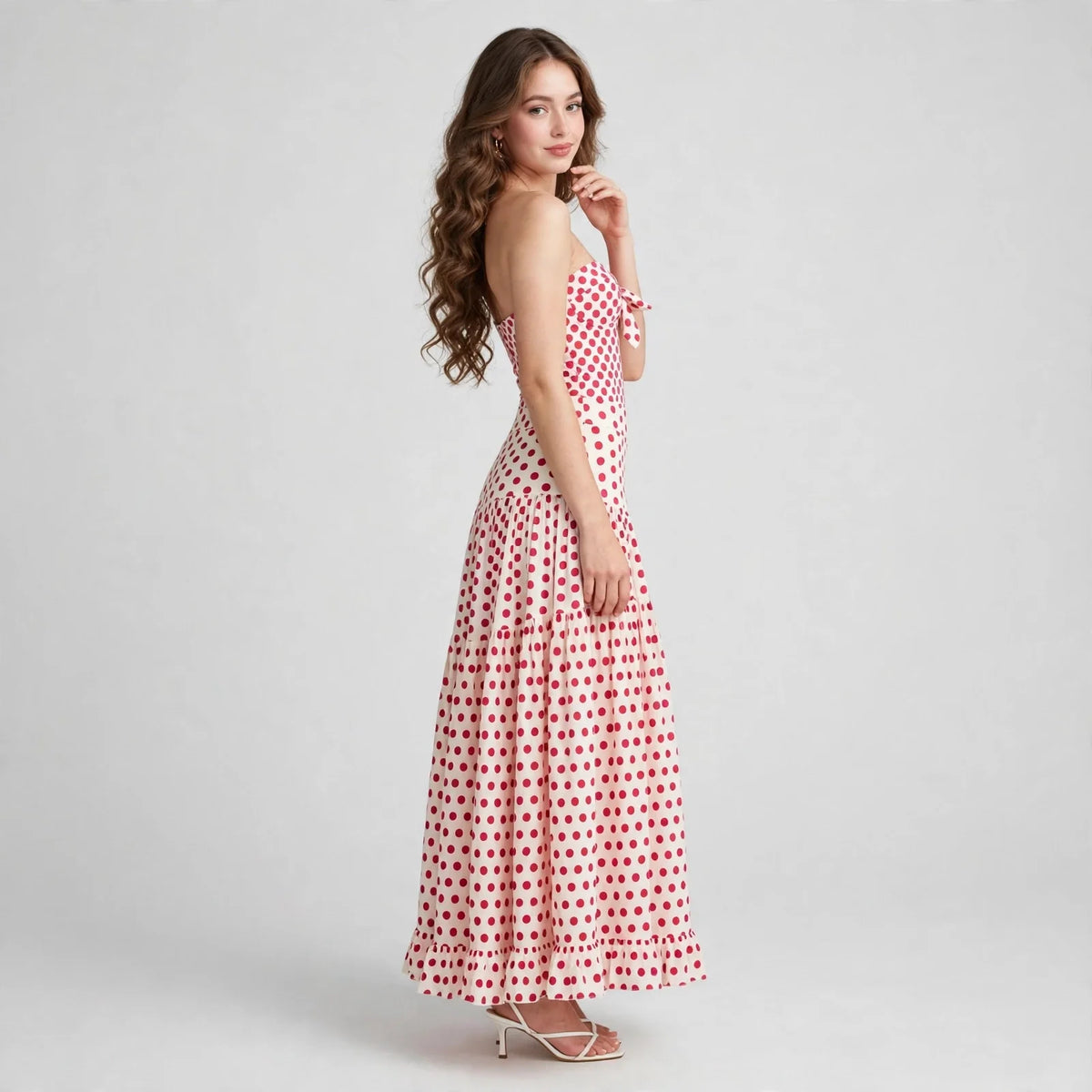 Side view of a red heart-print strapless swimsuit with matching tiered maxi skirt on a model, gray studio background.
