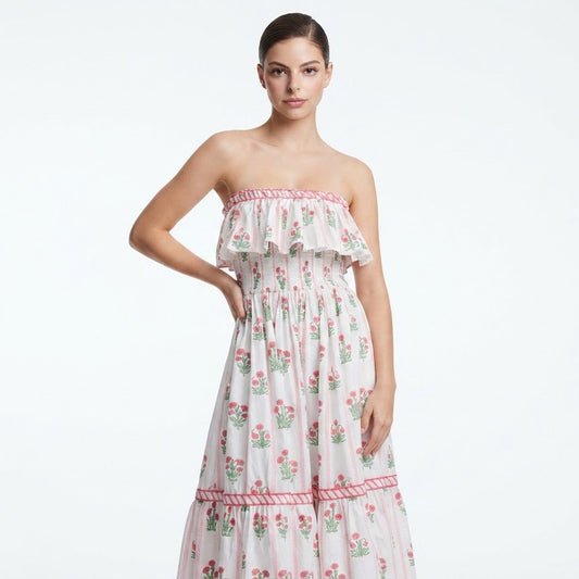 Woman in a white strapless floral maxi dress with pink ruffled trim and tiered skirt, front view, white studio background.