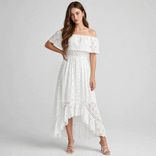Model in a white off-shoulder eyelet lace maxi dress with ruffled high-low hem and strappy sandals, gray studio background.