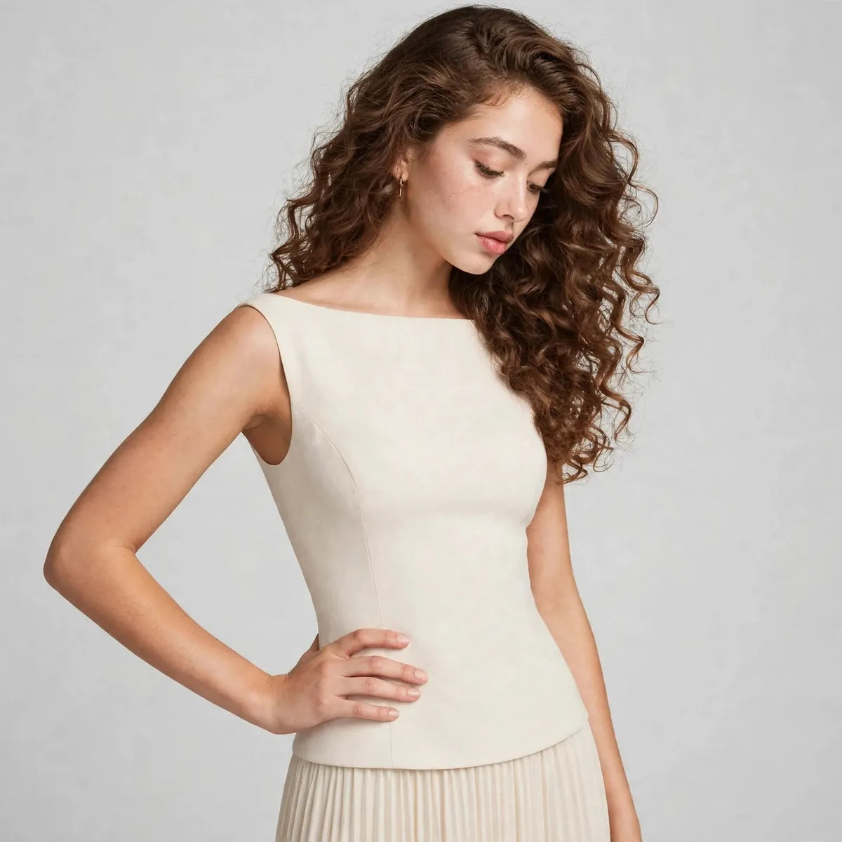 Close-up of a cream sleeveless maxi dress bodice showing the boat neckline and fitted waist, gray studio background.