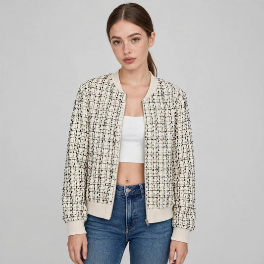 Front view of a woman in a cream and black tweed zip-up bomber jacket with ribbed trim, white crop top, jeans.