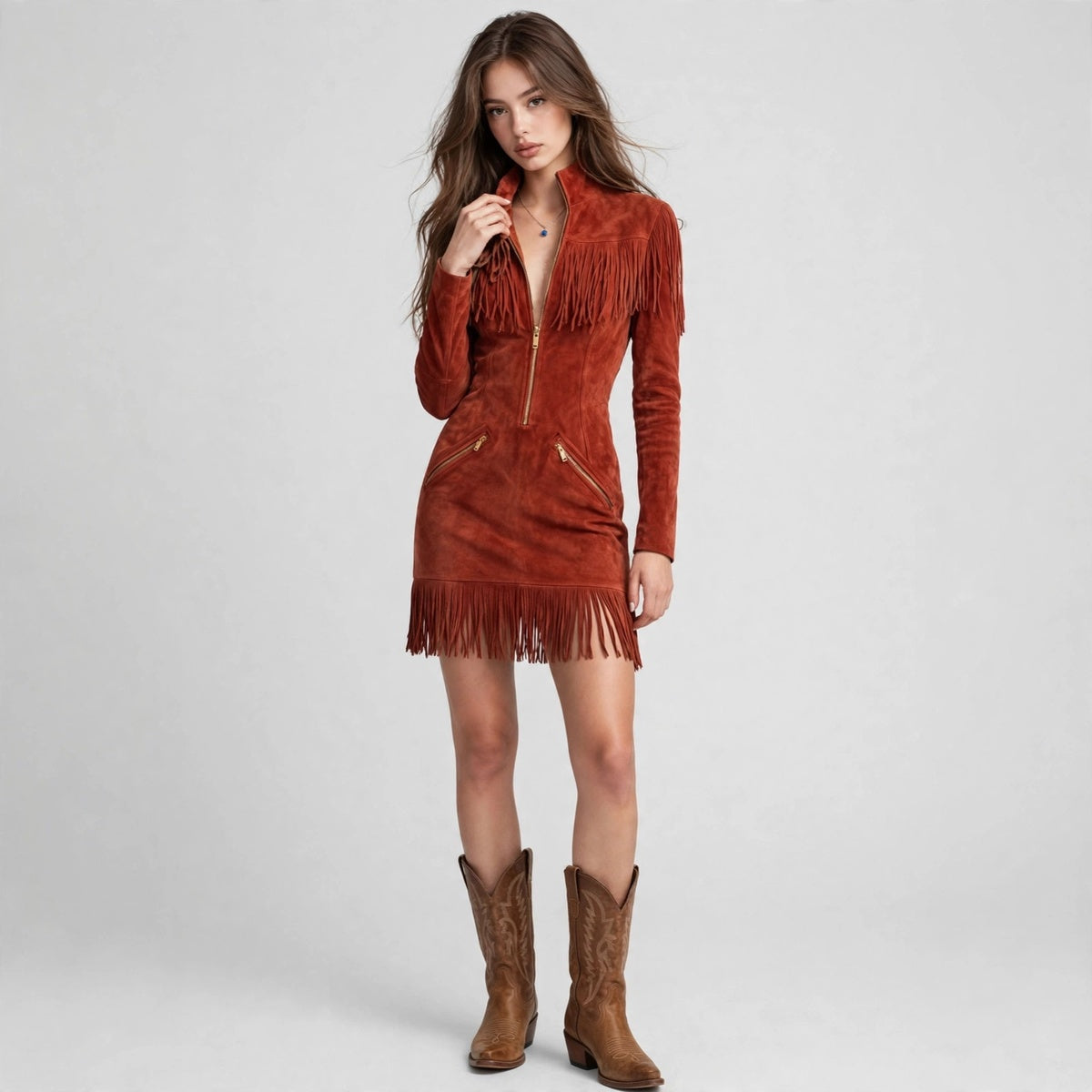 Woman modeling a rust-brown suede fringe mini dress with front zipper, long sleeves and high collar, brown cowboy boots.