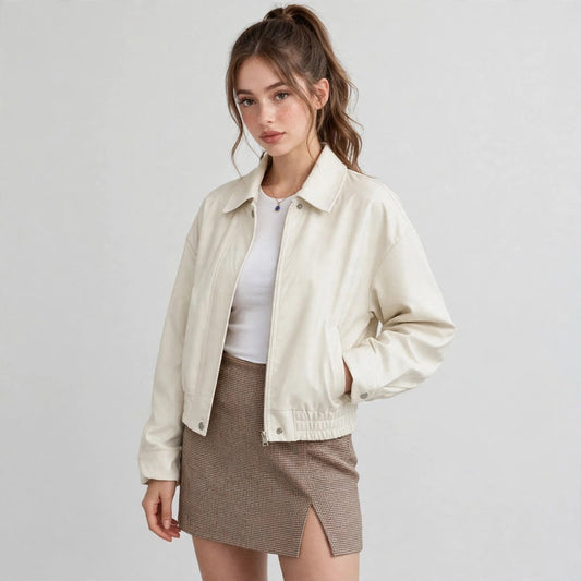 Front view of a cream cropped faux leather jacket with snap buttons and collar, styled with white top and brown skirt.