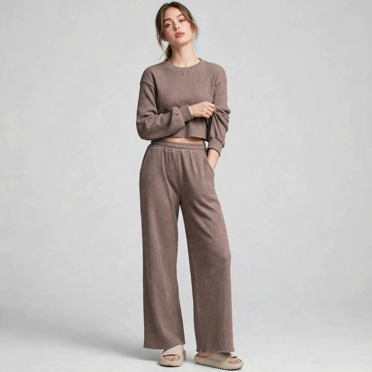 Model in brown waffle-knit cropped long-sleeve top and wide-leg pants set, front view, light grey studio backdrop.