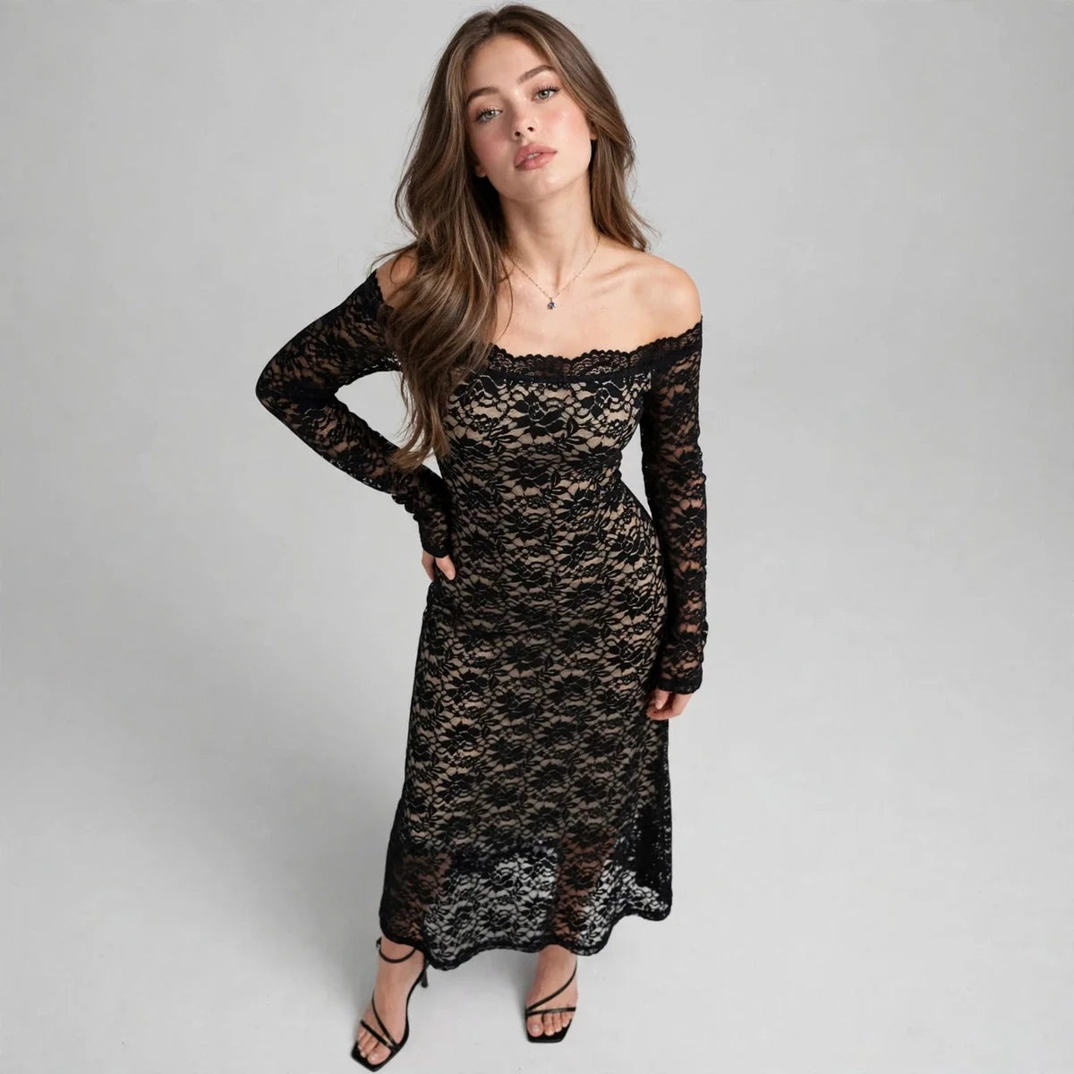 Front view of model posing with hand on hip in black off-shoulder long-sleeve lace maxi dress, grey studio background
