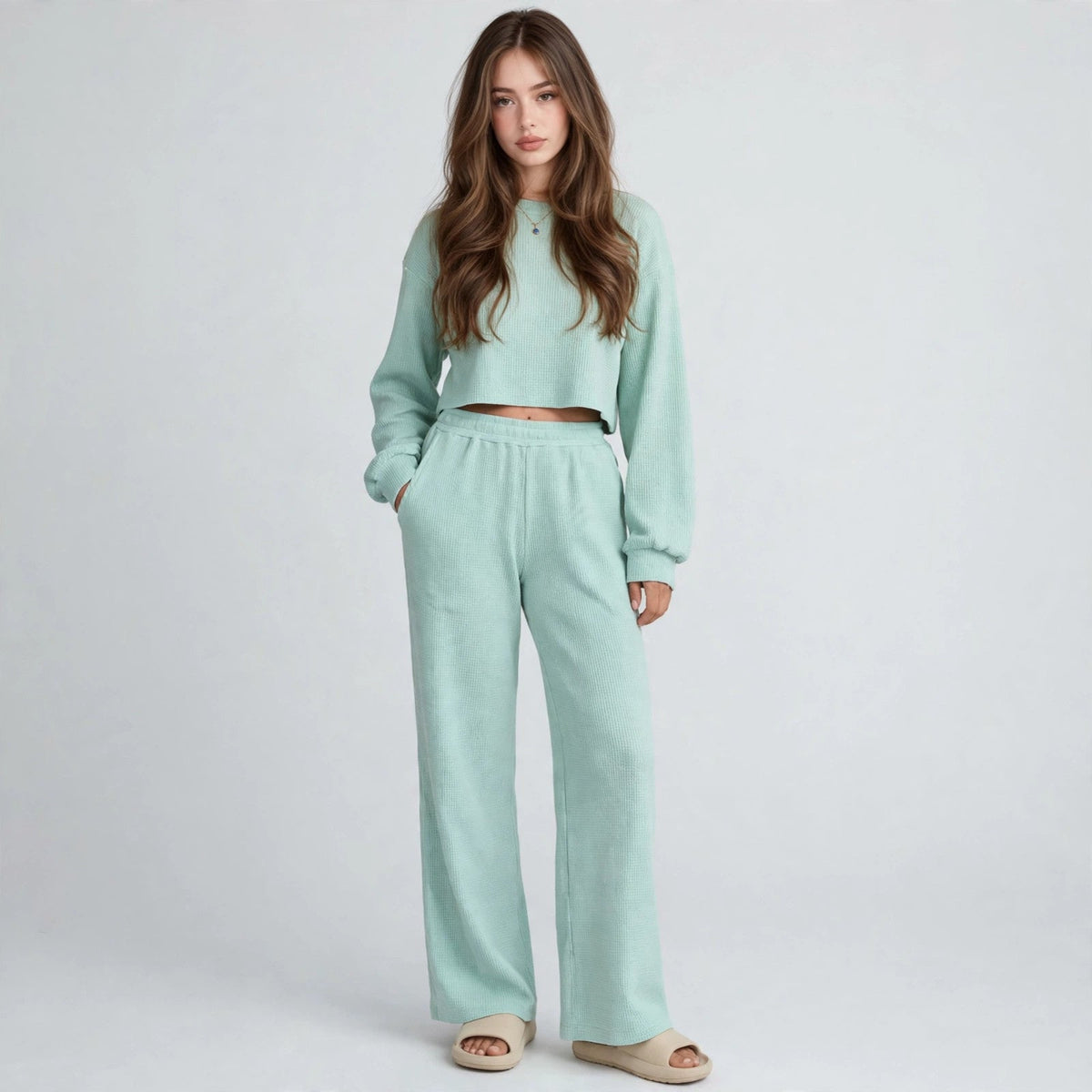 Model in mint waffle-knit loungewear set with cropped top and wide-leg pants, hands in pockets, front studio view.