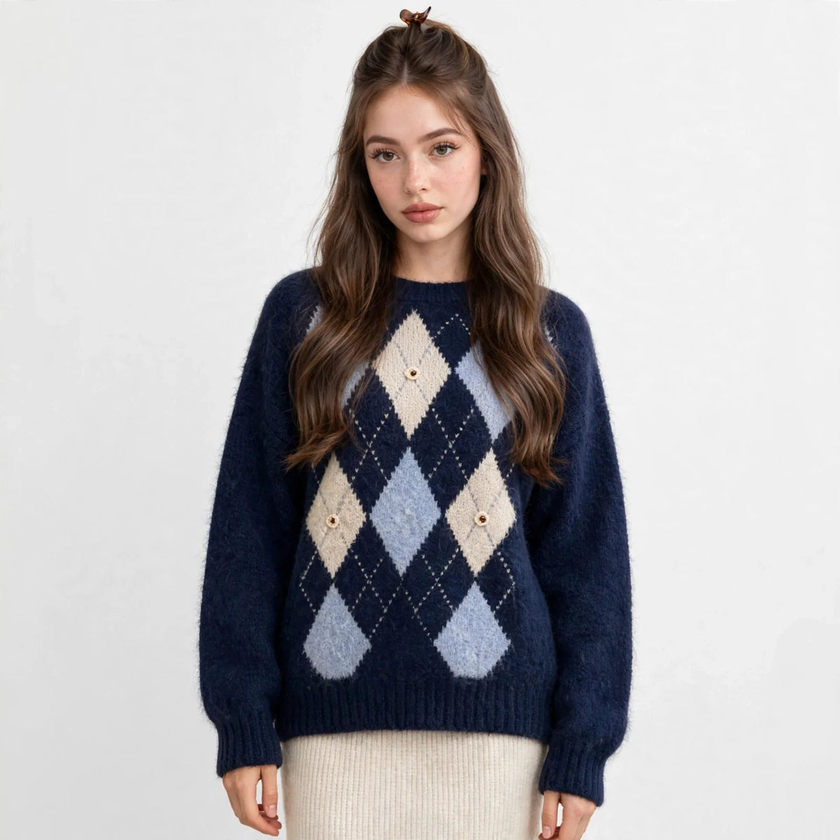 Front view of a navy argyle knit sweater with raglan sleeves and cream diamond pattern, white skirt, white studio background.