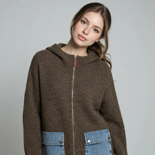 Close-up front view of a woman in a brown hooded zip-up knit cardigan with contrast denim patch pockets.