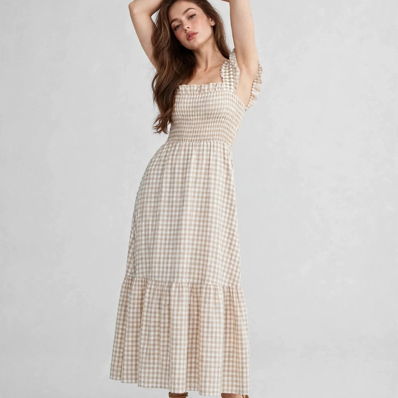 Model with arms raised in beige gingham plaid maxi dress with ruffle cap sleeves, smocked bodice, full-length studio view.