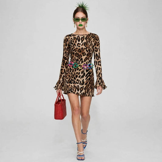Woman in a leopard-print long-sleeve mini dress with red handbag and blue heels, runway walk, light gray background.