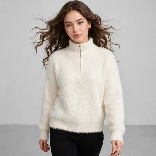 Model in a cream fuzzy half-zip sweater with black pants, front view, against a light gray studio background.