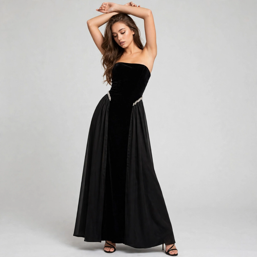 Front view of a woman with arms raised wearing a black strapless velvet maxi dress with a rhinestone waistband.
