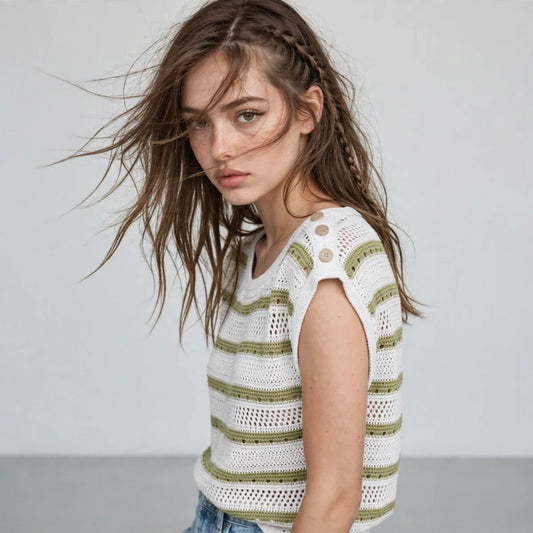 Close-up of a white crochet knit top with green stripes, cap sleeves and shoulder buttons, gray studio background.